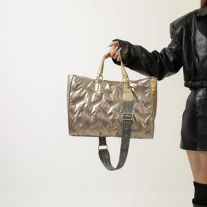 Detail of metallic champagne tote bag featuring quilted texture and geometric strap