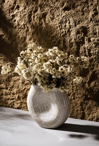 Close-up of matte off-white ceramic vase with hand-pinched texture and dried flower accents