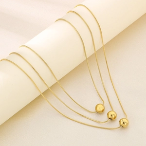 Macro shot of triple-layer gold snake chains with polished sphere charms on a display stand