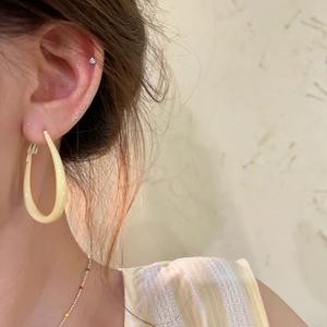 Detailed view of pale yellow oval resin hoop earring worn by a model in soft light