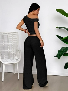 Rear view of black two-piece set featuring a one-shoulder top and high-waist wide-leg pants