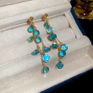 Dettaglio macro degli orecchini pendenti a frangia placcati oro 18k con perle blu