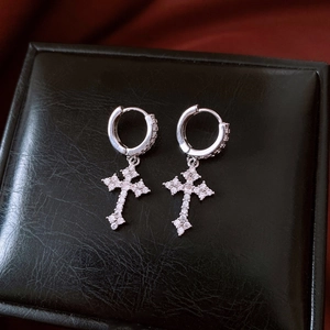 Detailed view of silver cross pendant earrings with white zircon on black leather