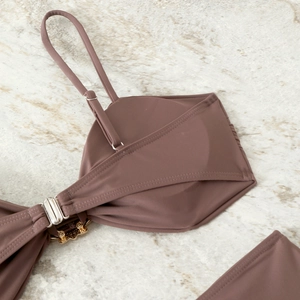 Close-up of brown bikini top with adjustable straps and gold floral charm detail