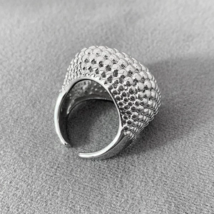 Makroaufnahme von silbernem, perlenbesetztem, breitem offenem Ring auf grauem Grund