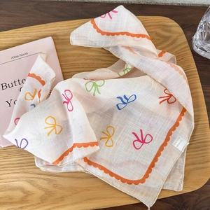 Detail of floral linen headscarf with bow patterns and orange wavy stitched edges