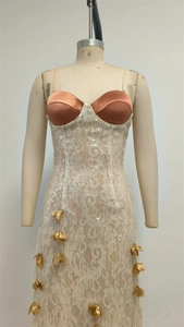 Détail d'une robe en dentelle à paillettes blanches avec feuilles d'or 3D et corsage satin