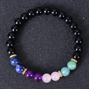 Macro shot of natural stone bracelet with black beads and colorful chakra accents