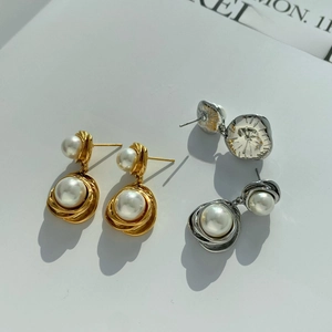 Detailed view of elegant pearl drop earrings with spiral texture in gold and silver