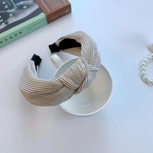 Close-up of silver-gray pleated wide headband with a stylish knot on a ceramic cup