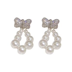 Elegant bow tie pearl earrings with sparkling crystals on a clean white background