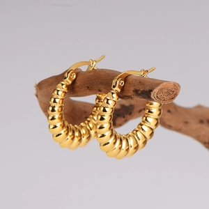 Elegant gold-plated twisted croissant hoop earrings displayed on a rustic wooden branch