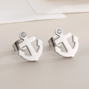 Macro shot of silver anchor earrings with sparkling zircon inlay on gray background