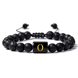 Détail des perles en pierre de lave noire et de la lettre O dorée sur le bracelet
