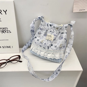 Detail of light blue canvas crossbody bag with cartoon prints, lace trim and heart embroidery
