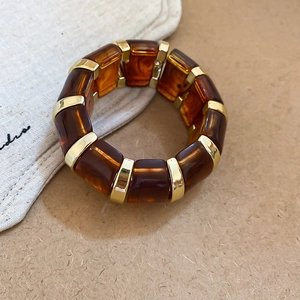 Detail of acrylic amber resin bracelet with gold metal accents and elastic band