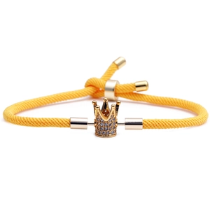 Détail du bracelet tressé jaune vif réglable avec pendentif couronne plaqué or