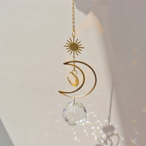 Detail of crystal suncatcher casting rainbow light spots on wall with golden moon design