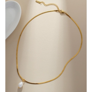 Macro shot of gold flat snake chain with an irregular white freshwater pearl pendant
