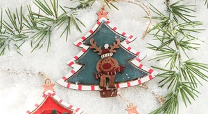 Detail of wooden Reindeer and Christmas tree ornament on pine branches with snow