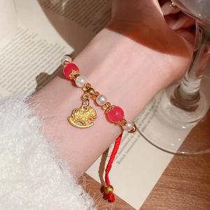 Détail d'un bracelet en perles rouges et blanches avec pendentif cheval à bascule doré