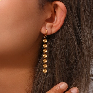 Close-up of long gold earrings with layered sunburst discs on model for scale