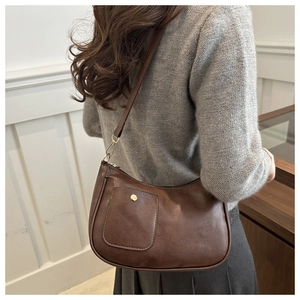 Brown vintage square shoulder bag with front pocket and adjustable strap on a model