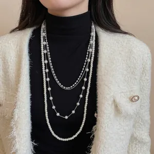 Elegant multi-layered pearl necklace with silver chains worn on a chic black turtleneck