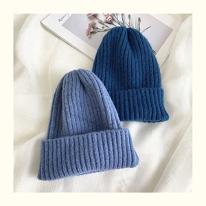 Detail of navy and light blue ribbed knit beanies on white cotton with a soft texture