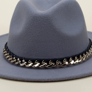 Detail of grey wool fedora hat with elegant black ribbon and gold chain decoration