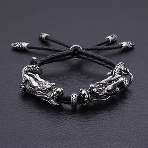 Vue détaillée des têtes de dragon rétro en argent sur bracelet en cuir tressé noir