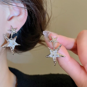 Detail of silver star pendant earrings with sparkling cubic zirconia on model ear