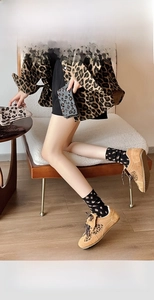 Detail of leopard print heart socks styled with khaki sneakers and warm autumn outfit
