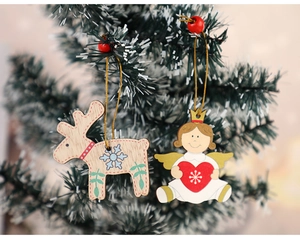 Detailed view of reindeer and angel wooden Christmas ornaments hanging on a festive tree branch