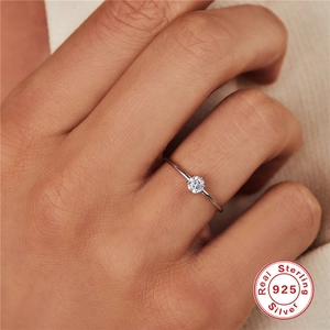 Close-up of minimalist sterling silver engagement ring with a round-cut diamond on finger