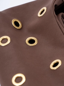 Detailed close-up of golden metal rivets on dark brown suede material of the shoulder bag
