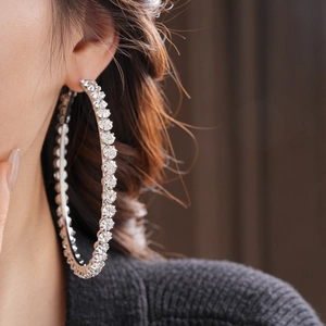 Macro shot of silver oversized hoop earrings with sparkling rhinestones worn by a model