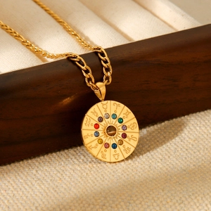 Macro dettaglio della collana zodiacale dorata con pietre colorate su portagioie in legno