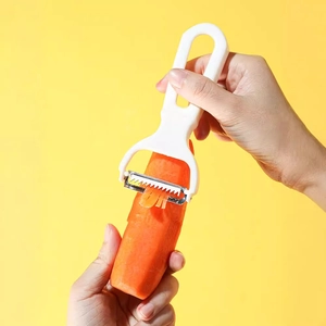 Dual-blade stainless steel vegetable peeler peeling a carrot on yellow background