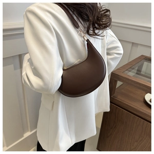 Detail of dark brown crescent shoulder bag with smooth leather finish and gold buckle