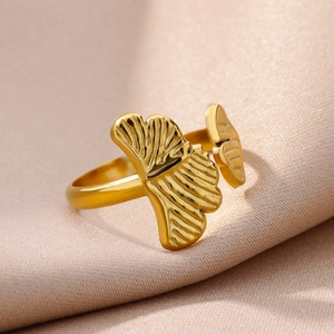 Detailed view of gold ginkgo leaf ring with textured finish on champagne silk fabric