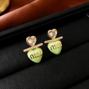Macro detail of heart-shaped earrings with light green enamel and crystal embellishments