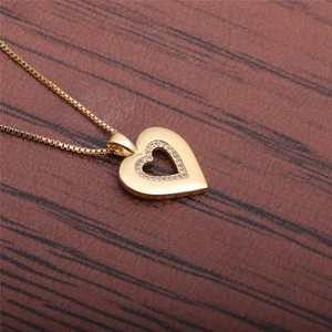 Elegant gold heart pendant necklace with shimmering crystals on a wooden background