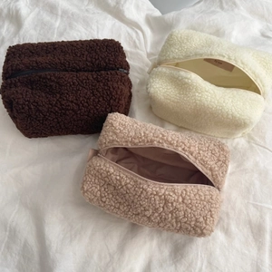Detailansicht von drei flauschigen Kosmetiktaschen aus Lammwolle in Creme, Braun und Beige