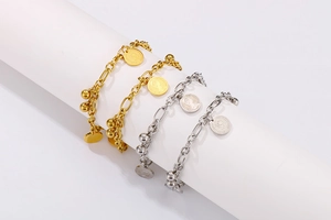 Dettaglio di ciondoli moneta vintage su bracciali in acciaio al titanio oro e argento
