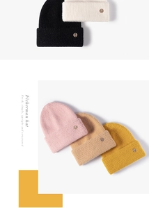 Close-up of five colorful knitted beanies with metallic M logos and thick textures