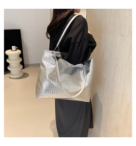 Detailed view of silver woven tote bag on shoulder showing large capacity and shiny texture