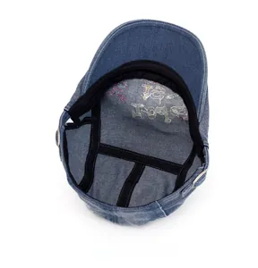 Internal detail of washed denim cadet cap showing sweatband and colorful embroidery
