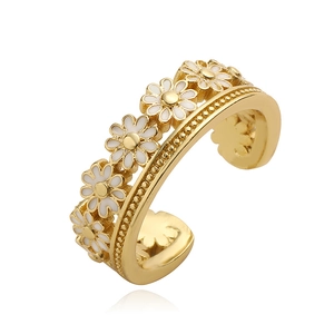 Detailed close-up of a golden open ring featuring white enamel daisy petals and polished finish