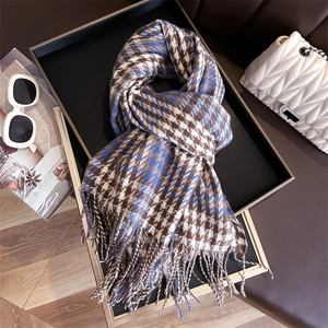Detail view of brown and blue houndstooth scarf with elegant fringes on a black tray